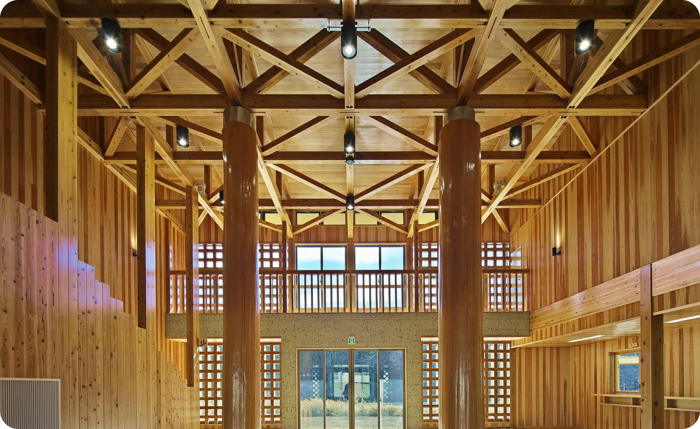 太い丸太柱と天井の梁組みが美しい、開放的な大規模木造建築の内観